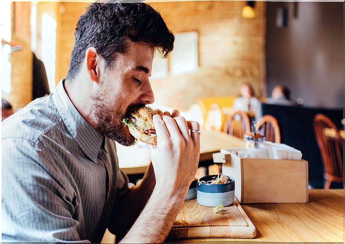 Man fast eats a hamburger.