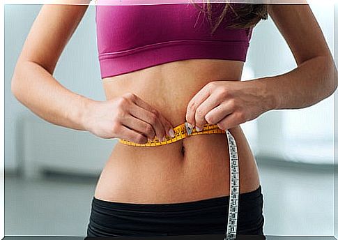 Woman measuring her abdomen with a tape measure after following a ketogenic diet