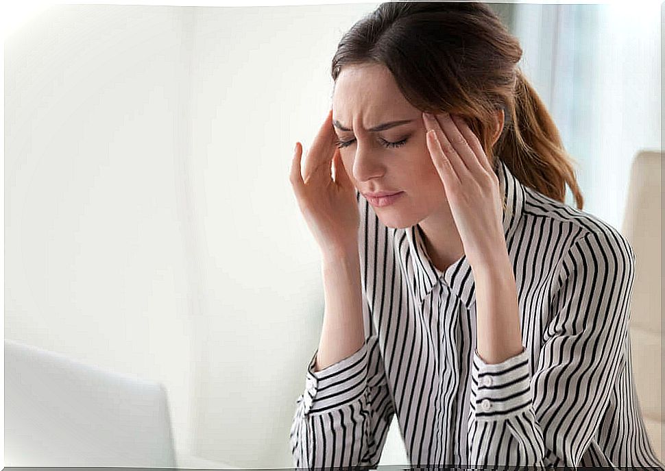 Woman in front of the computer with headache.