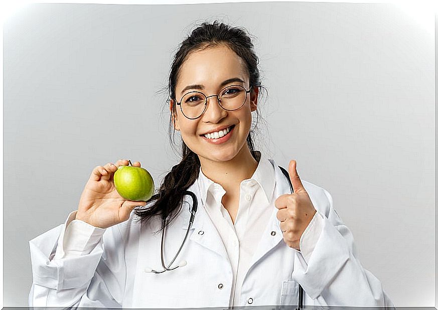 Female doctor holding a green apple.